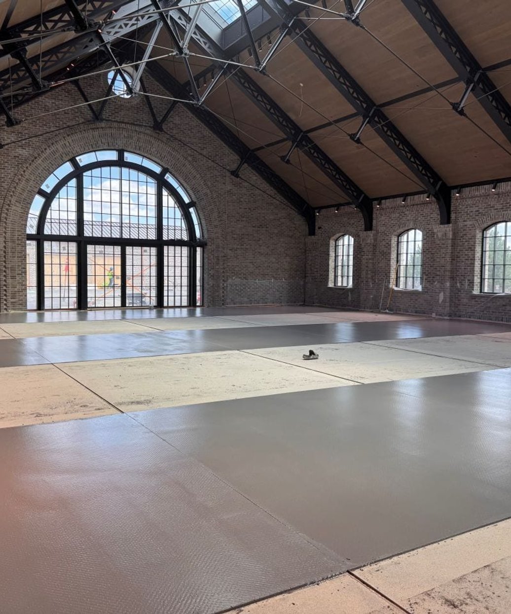 Concrete overlay being installed in a brick hall with arched windows
