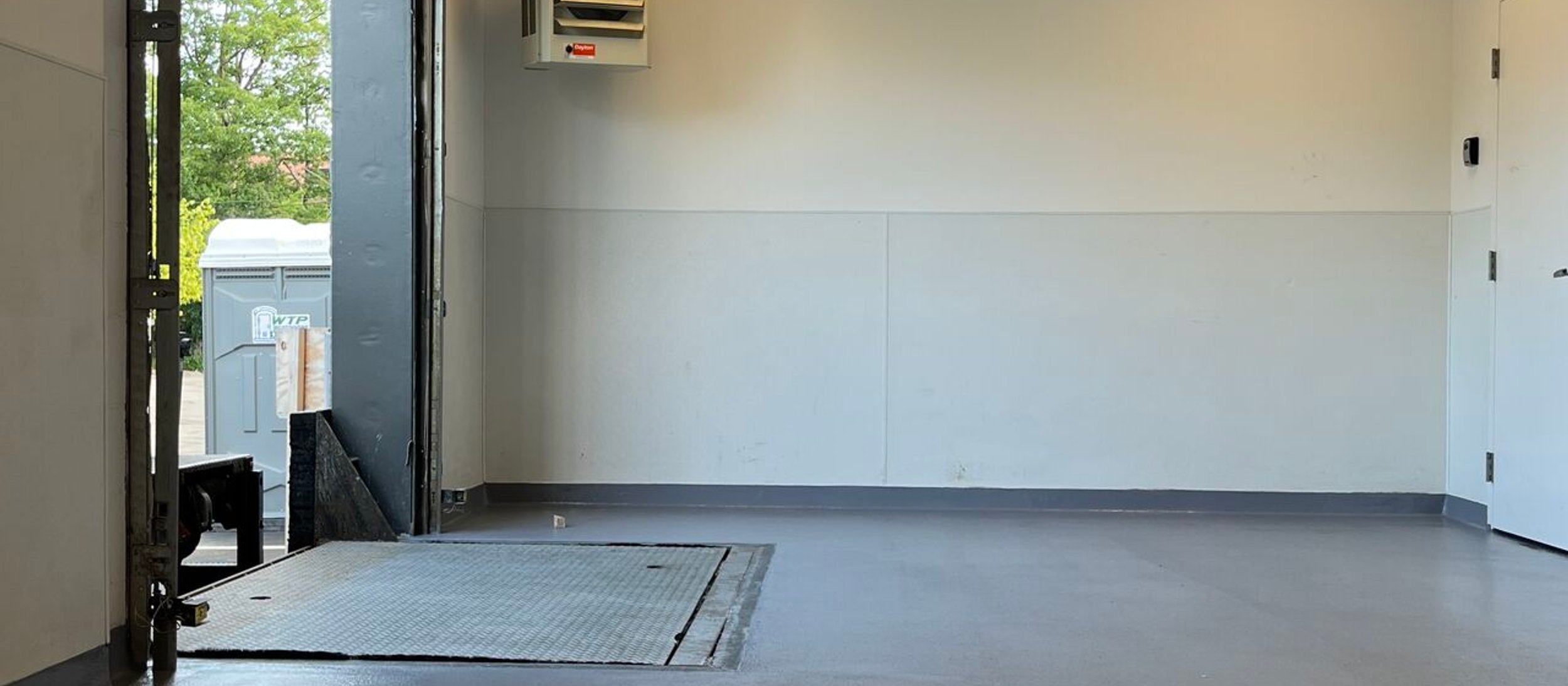 Gray epoxy floor in a loading area with an open roll-up door