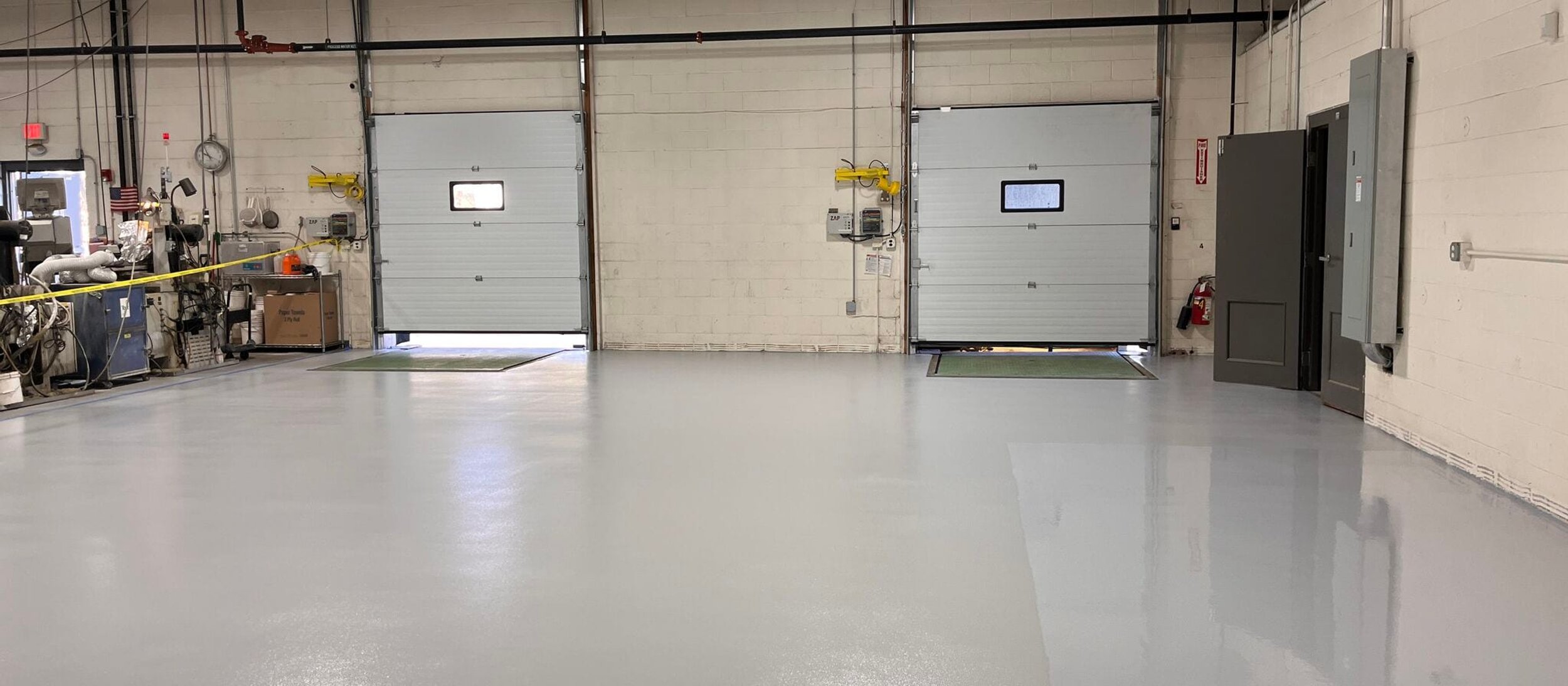 Gray epoxy floor in a facility bay with roll-up doors